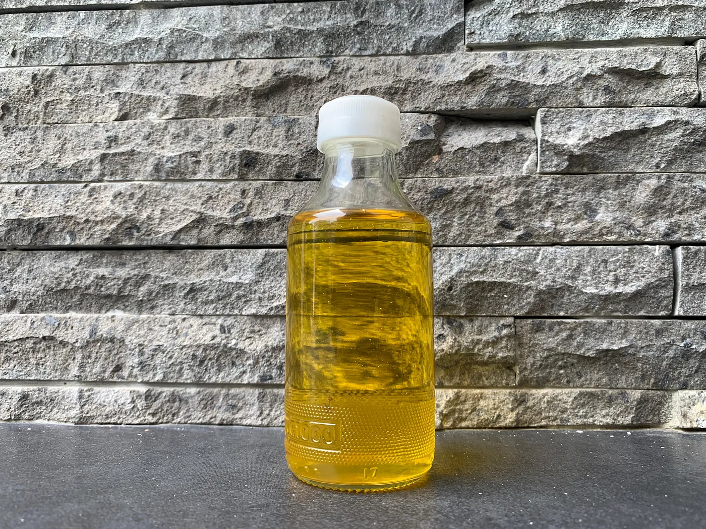 A bottle of kapok seed oil placed on a laboratory table, showcasing its clear golden color, highlighting its potential for biotechnology applications in sustainable products and renewable energy.